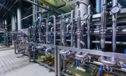 Industrial stainless steel pipes connected with vats and control valves.