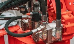 Hydraulic power unit mechanical valve with pipes and connections on heavy industry machine close-up.